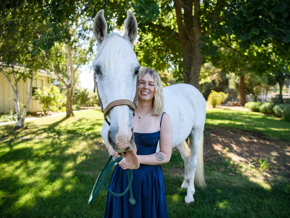 Sky Allen standing beside a white horse